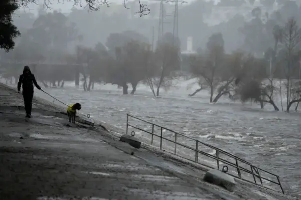 A man walking his dog on the edge of the Los Angeles River in the city on Sunday.Credit...Damian Dovarganes/Associated Press